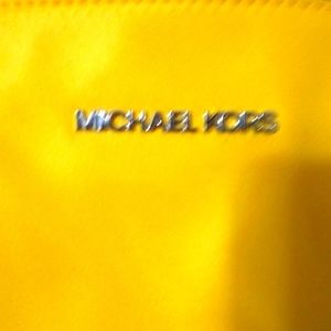 Michael Kors pocket book It a yellow short strap pocket book trimmed in black.